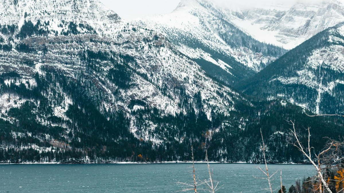 Breathtaking snowy mountain landscape in Glacier National Park, BC, Canada with serene lake in foreground.