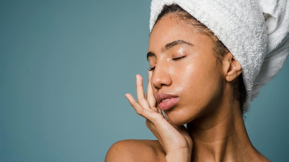 Serene portrait of a woman with a towel turban, eyes closed in a beauty ritual.