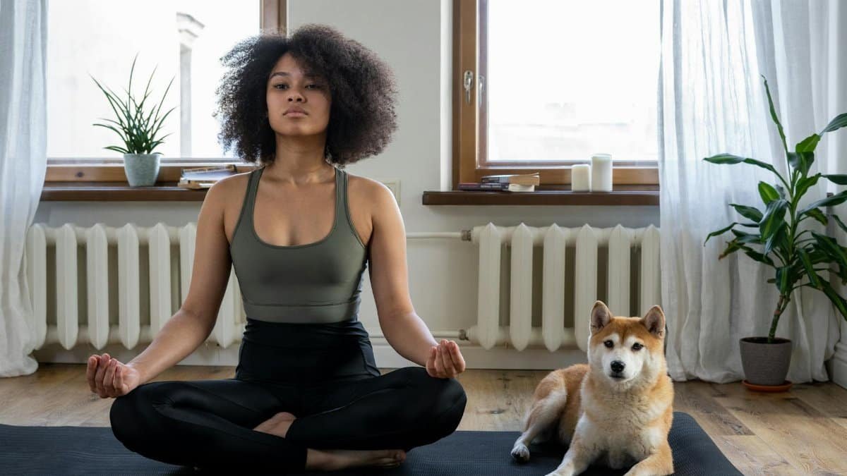 A woman practices yoga at home with her Shiba Inu dog, embracing a relaxing morning.