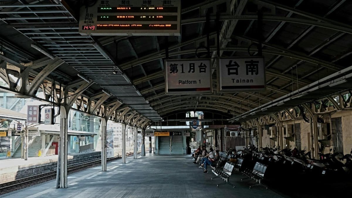 Empty train station platform in Tainan with benches and signs, creating a serene urban scene.