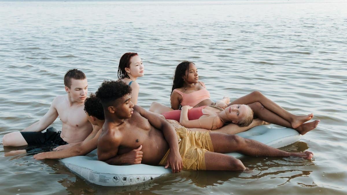 A diverse group of teenagers relaxing on a float in the sea, enjoying a summer vacation.