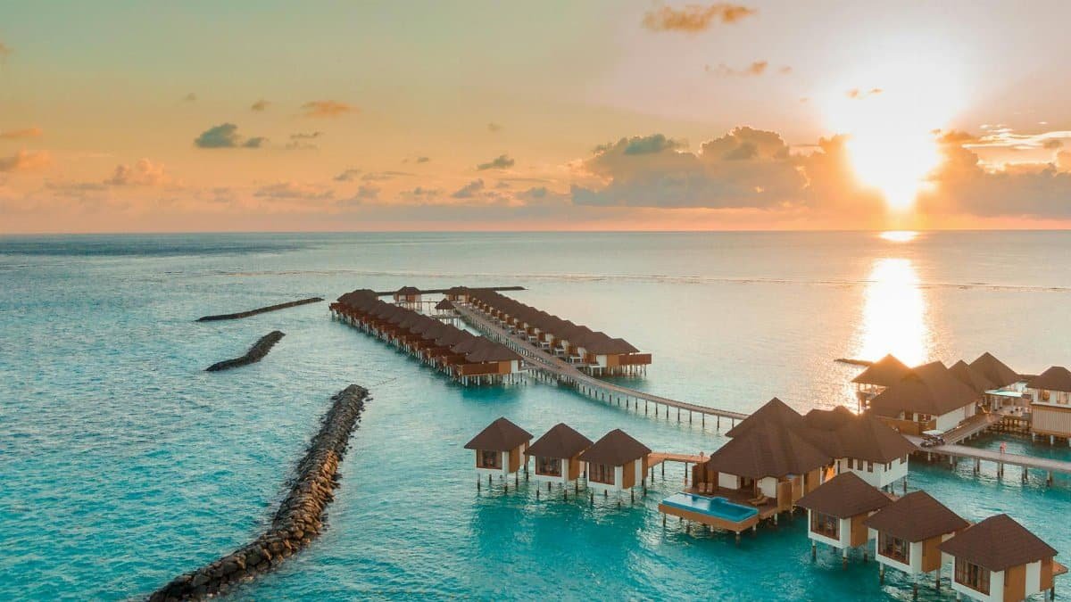 A breathtaking view of luxurious overwater villas in the Maldives at sunset.
