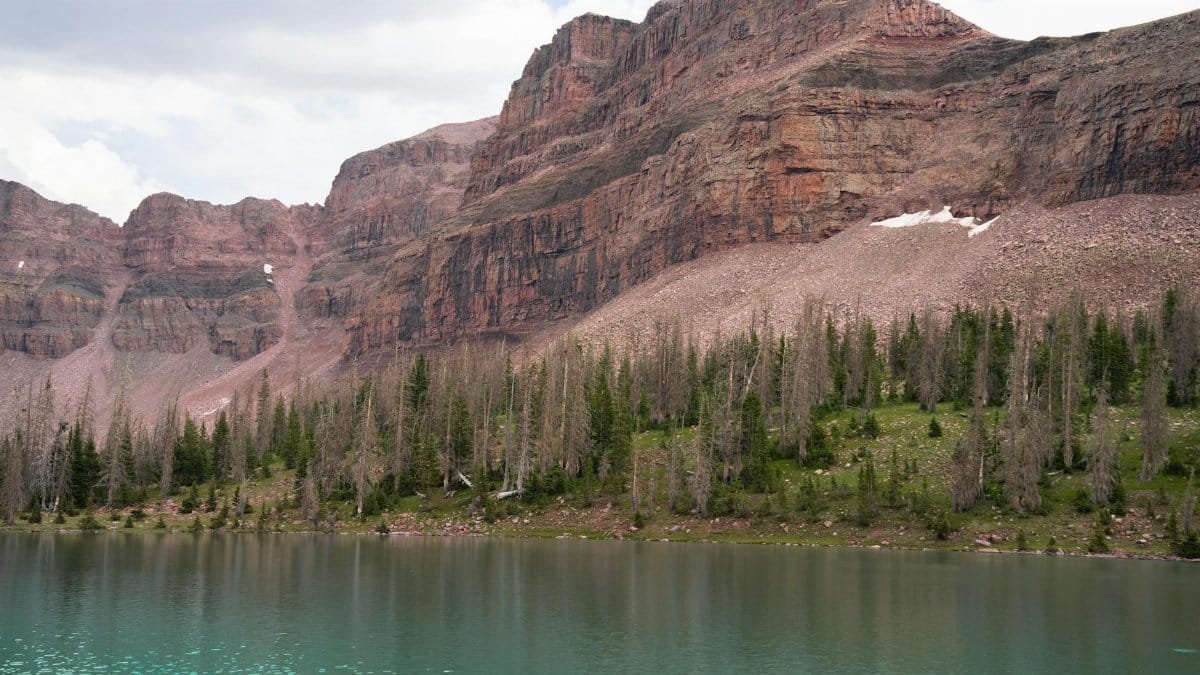 A tranquil mountain lake with reflecting waters and rugged cliffs in Uinta National Forest.