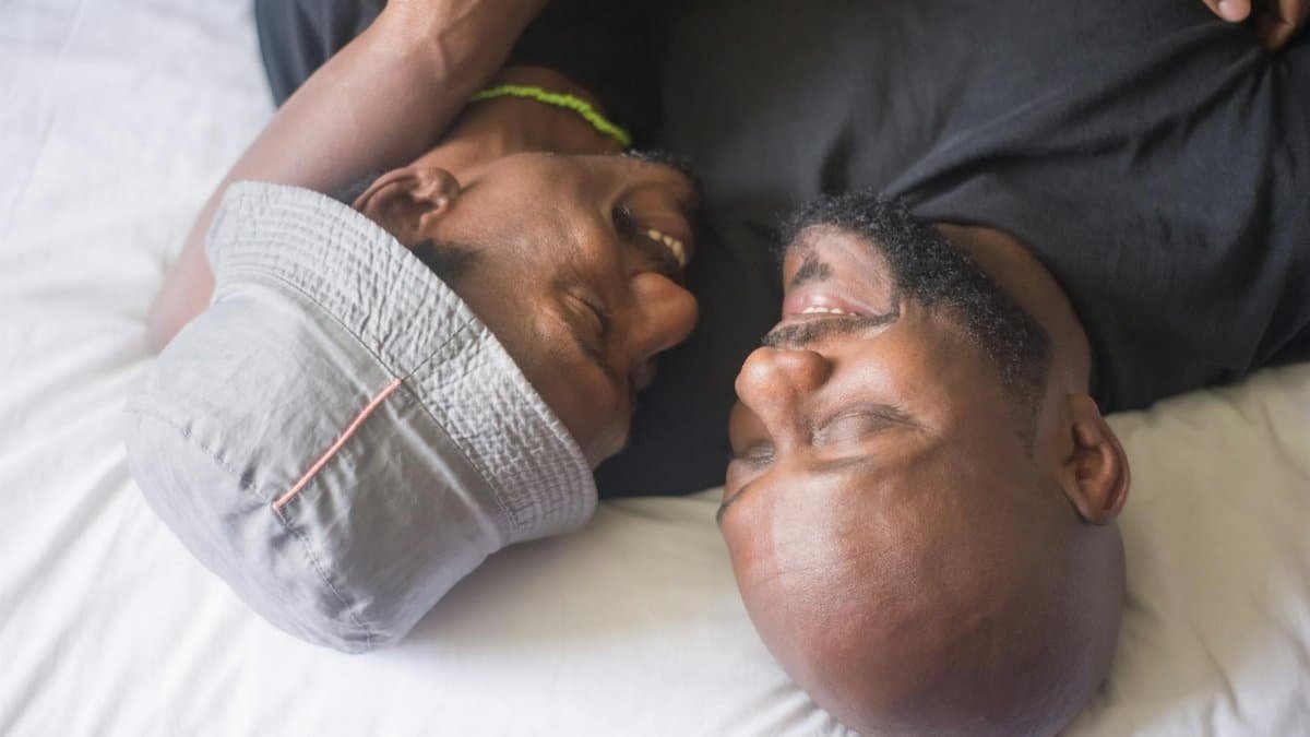 A tender moment of affection between two men relaxing and cuddling indoors.