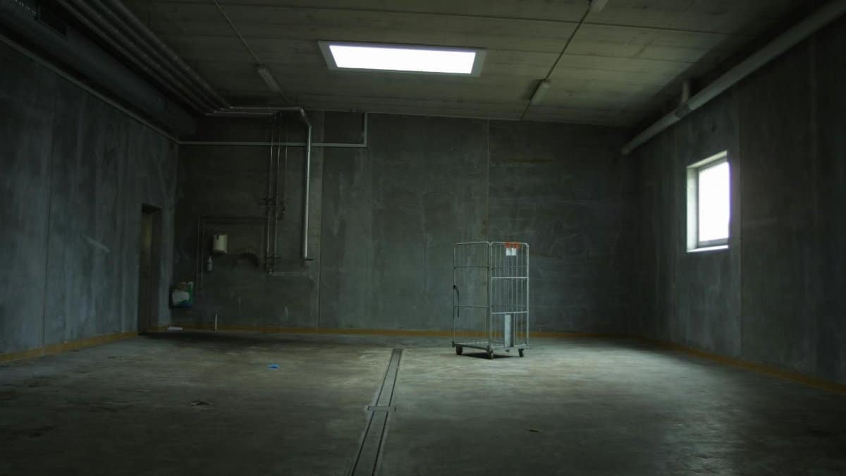 Dark empty industrial room with an abandoned cart, highlighting isolation and emptiness.
