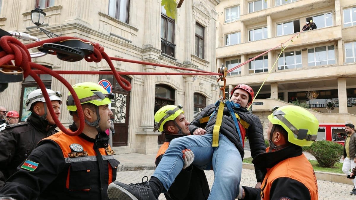 Firefighters perform a rescue operation during an emergency response drill in a city setting.