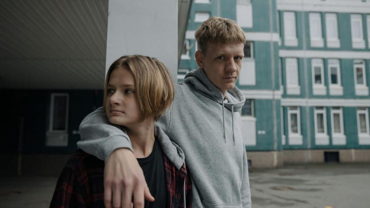 Two brothers standing outside a building in casual attire, expressing sibling bonding.