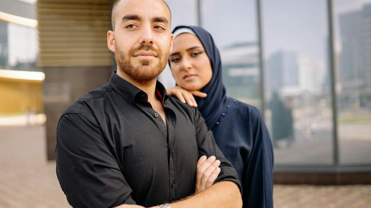 Portrait of a confident young Muslim couple standing together outside an urban building.