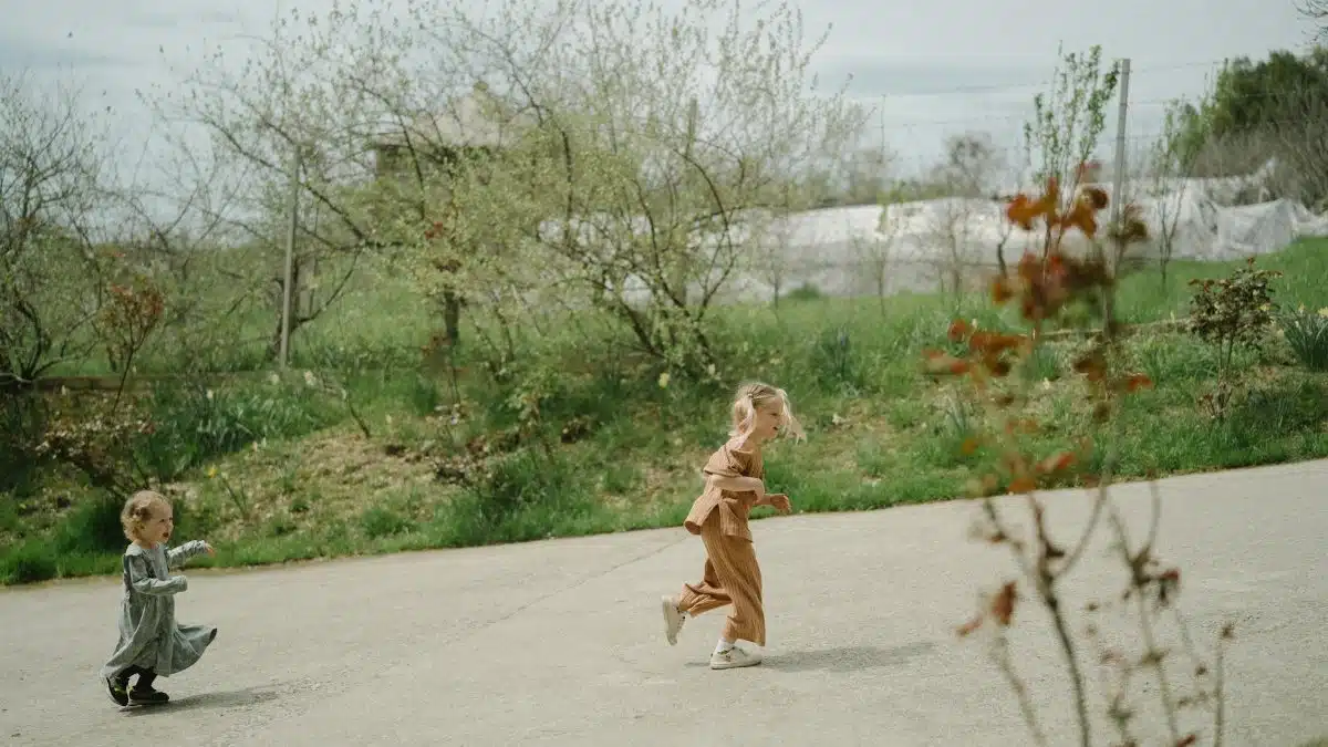 Two young children joyfully running in a green outdoor setting, capturing the essence of playful freedom.