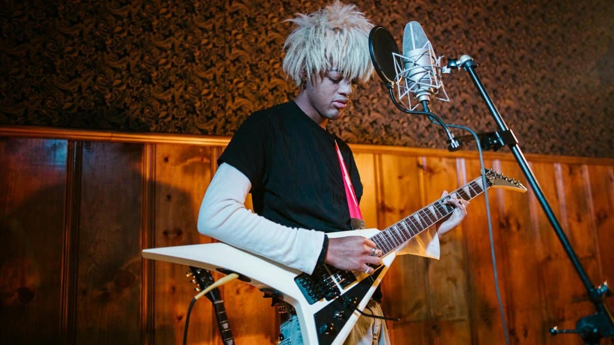 A young guitarist performs passionately in a music studio with an electric guitar and microphone.