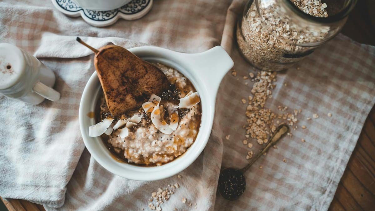 A cozy flatlay of oatmeal served with pear, coconut shavings, and honey.