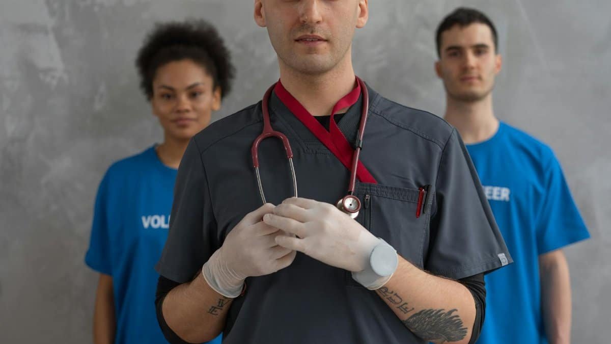 Portrait of a healthcare professional with volunteers in blue shirts, showing teamwork.
