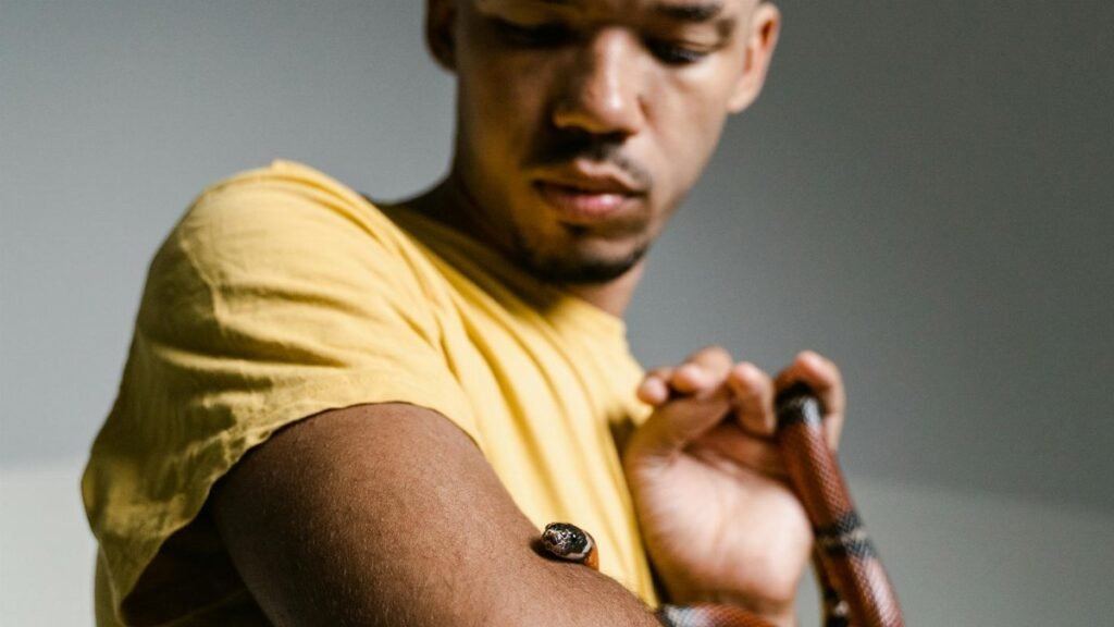A man faces his fear by holding a snake, symbolizing courage and personal growth.