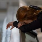A redheaded woman in deep prayer, leaning on a church pew in a serene atmosphere.