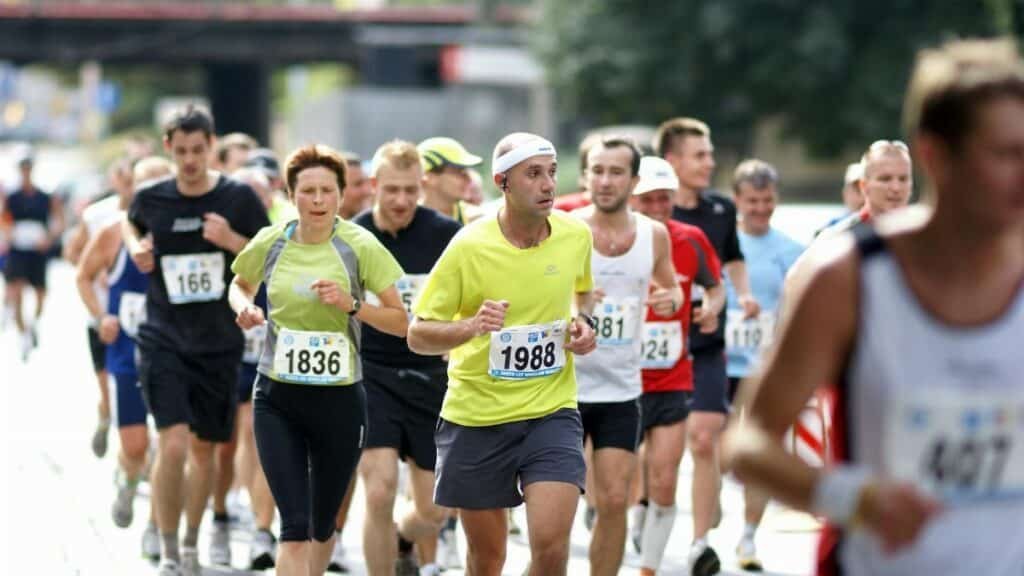 A diverse group of runners actively participating in a marathon on a city street during the day.