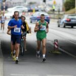 Two male athletes running in an urban marathon event, showcasing endurance and competition.