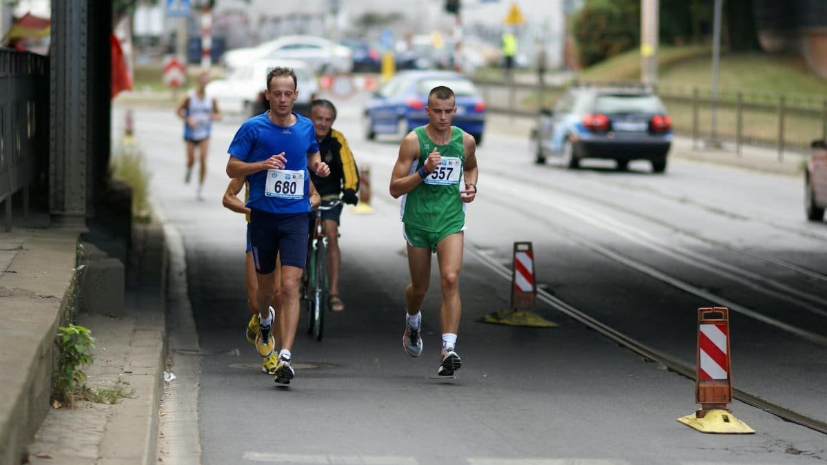 Two male athletes running in an urban marathon event, showcasing endurance and competition.