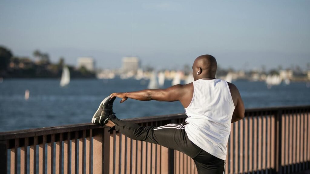 African American man stretching by the water, promoting outdoor fitness and healthy lifestyle.