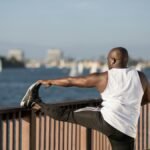 African American man stretching by the water, promoting outdoor fitness and healthy lifestyle.