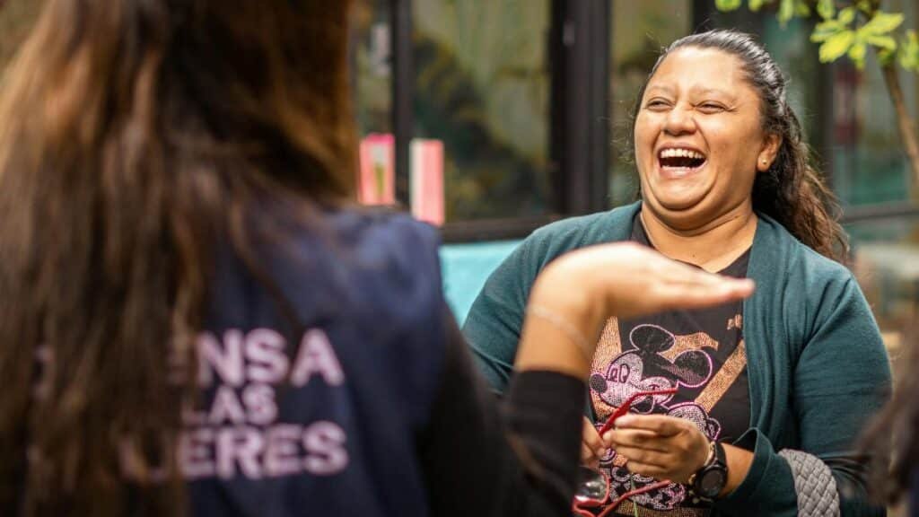 Two women sharing a moment of laughter outdoors in Ciudad de México, showcasing happiness and friendship.