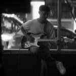 A guitarist performing intimately indoors with a focus on musical expression.