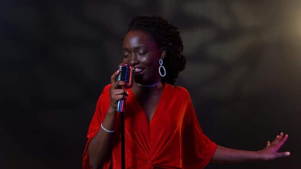 An elegant female singer in a vibrant red dress performs passionately with a vintage microphone.