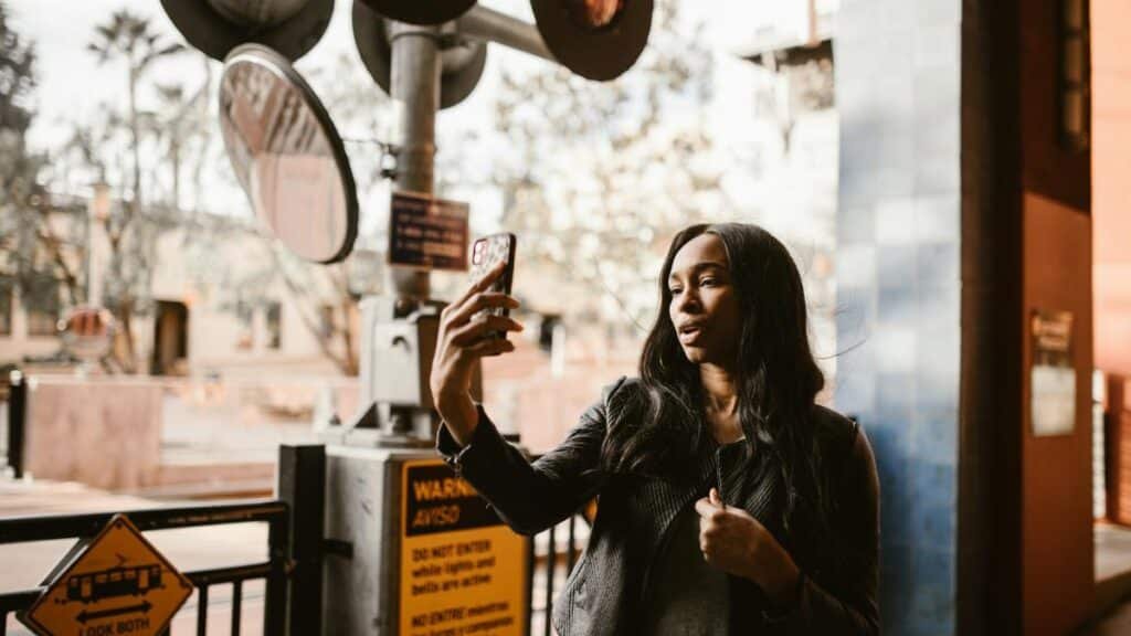 Stylish woman takes a selfie at a city crosswalk, capturing urban life.