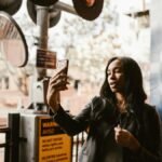 Stylish woman takes a selfie at a city crosswalk, capturing urban life.