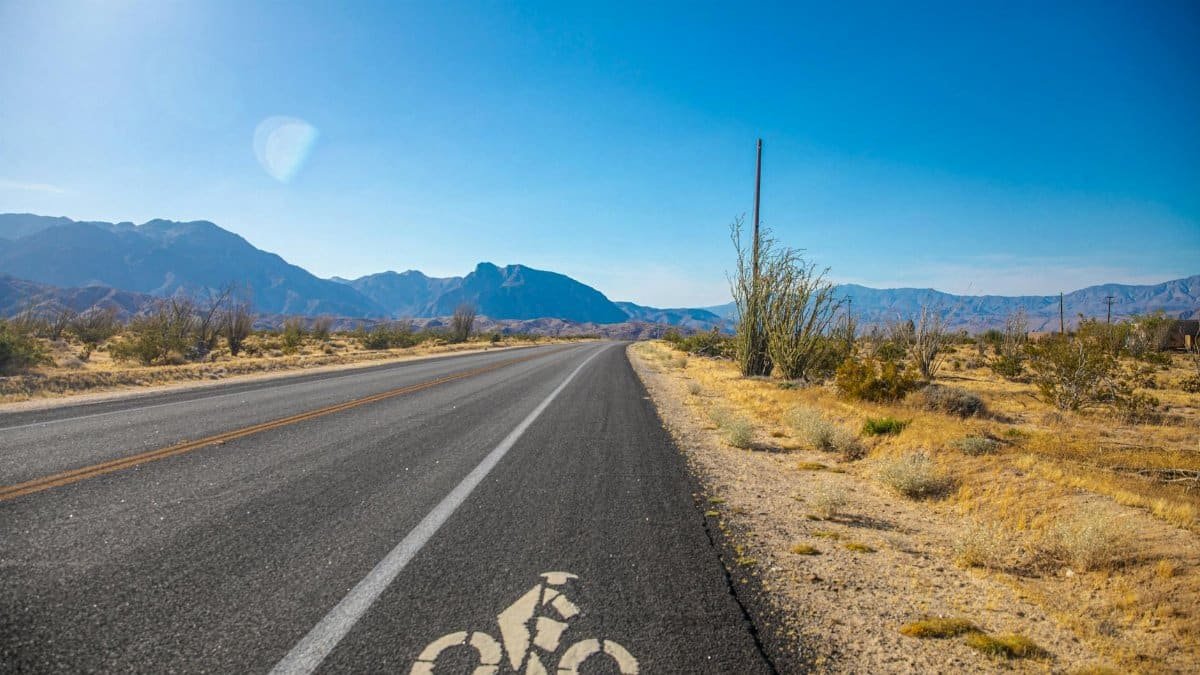 A sunny day on a deserted highway with a marked bike lane through a scenic desert landscape.