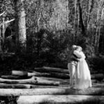 A tender moment between an elderly couple embracing in a sunlit forest clearing, depicting love and connection.