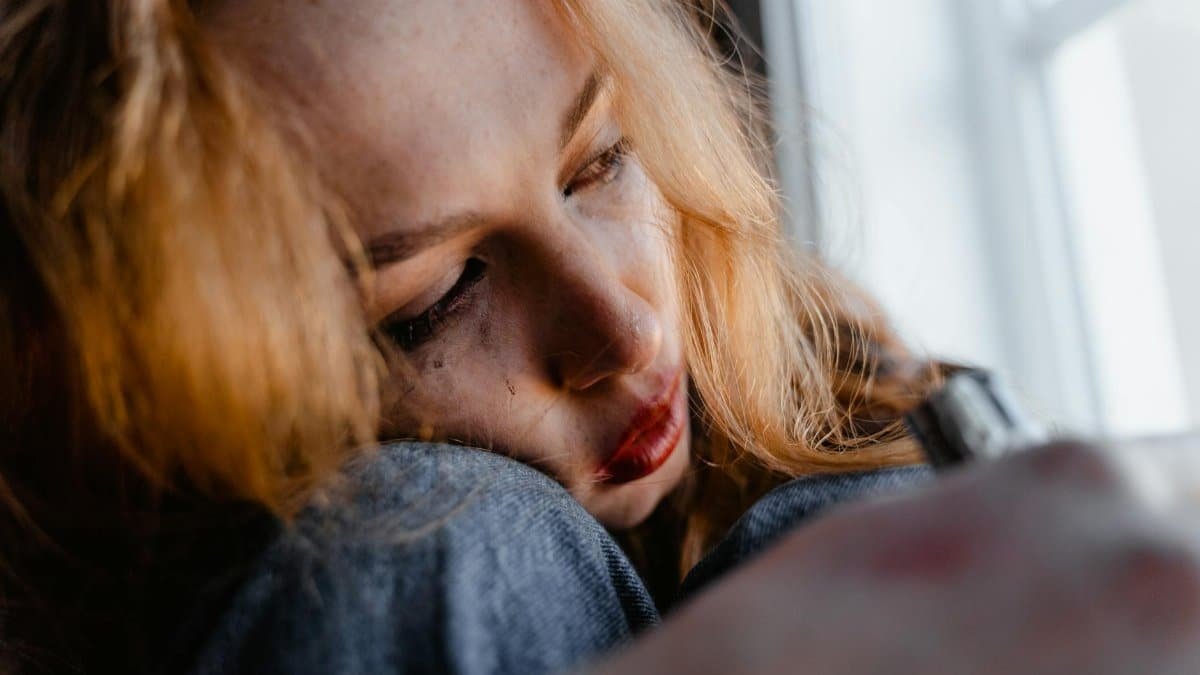 Close-up of a woman with red hair in a thoughtful and emotional moment indoors.