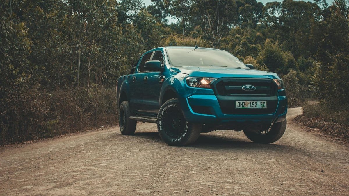 Blue Ford Ranger parked on a dirt road surrounded by forest, ready for an adventure.