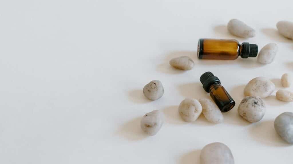 Minimalist arrangement of essential oil bottles surrounded by stones on a light background.