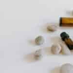 Minimalist arrangement of essential oil bottles surrounded by stones on a light background.