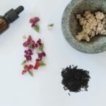 Flat lay of natural skincare ingredients including flowers, black seeds, and a dropper bottle.