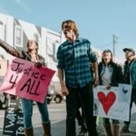Diverse group of protesters holding signs advocating justice and peace in a peaceful rally.