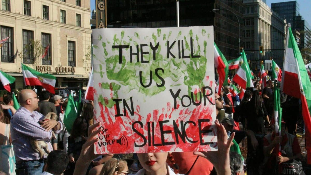 A large crowd gathers in Vancouver to protest for democracy and freedom, holding signs and flags.