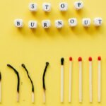 Conceptual image of burnout prevention with matches and letters on yellow background.
