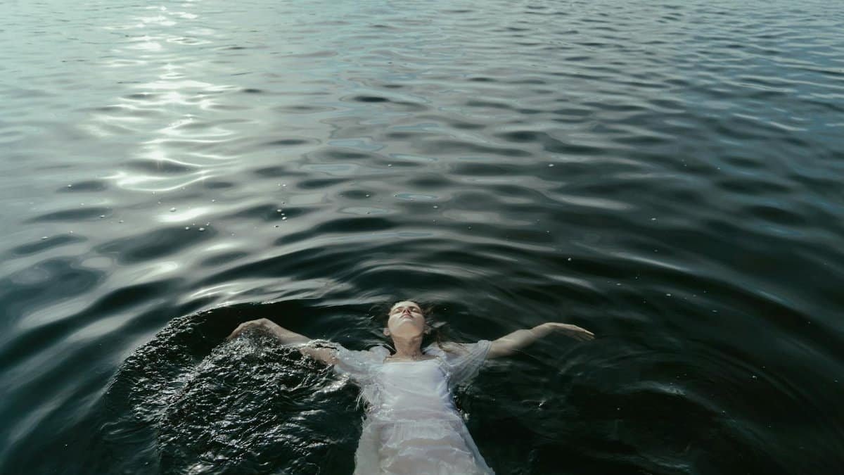 A woman peacefully floating in calm water, exuding tranquility and freedom.