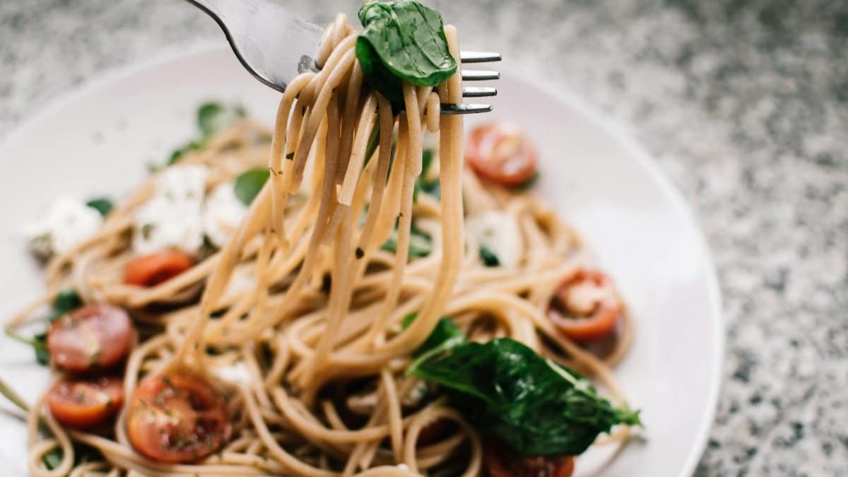 Delicious whole wheat pasta with fresh spinach, cherry tomatoes, and feta cheese in a close-up shot.