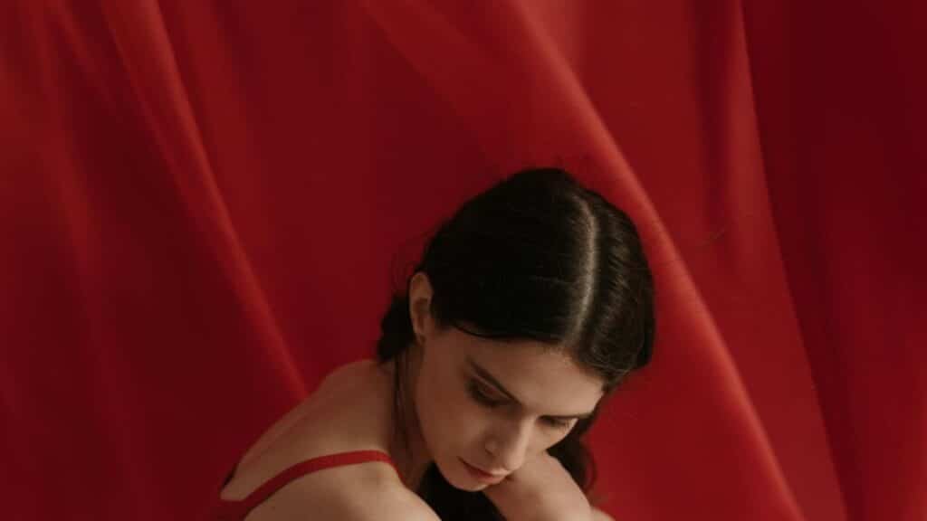 A thoughtful woman in red fabric, creating a serene and artistic mood.