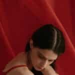 A thoughtful woman in red fabric, creating a serene and artistic mood.