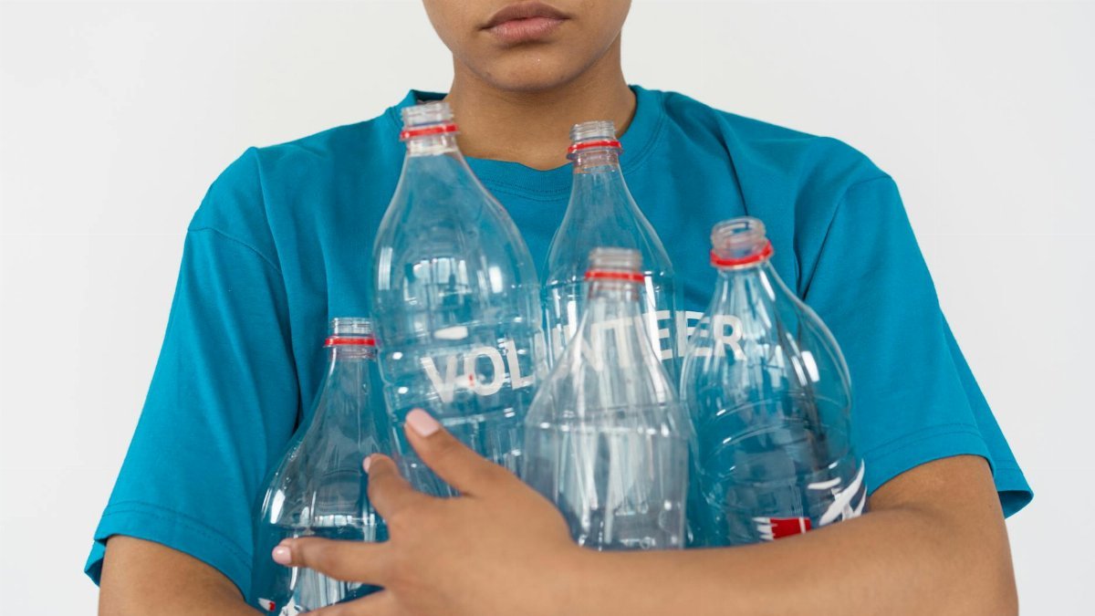 Portrait of a young volunteer with empty plastic bottles, promoting recycling and sustainability.