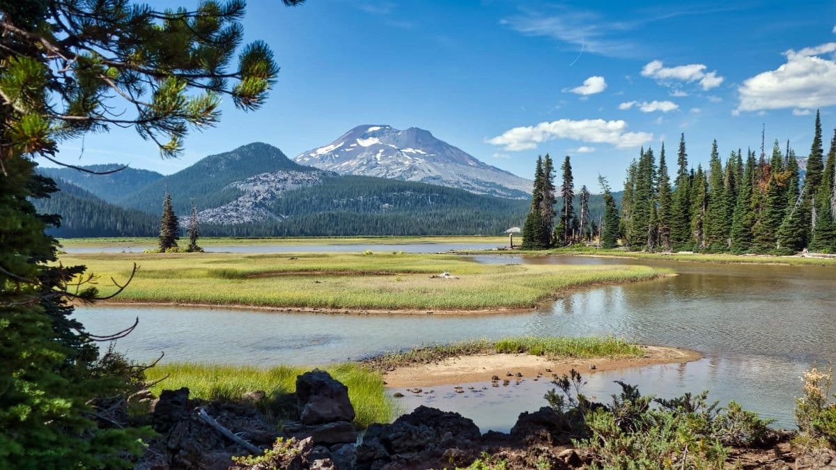 Scenic view of a tranquil lake surrounded by mountains and trees in Bend, Oregon.