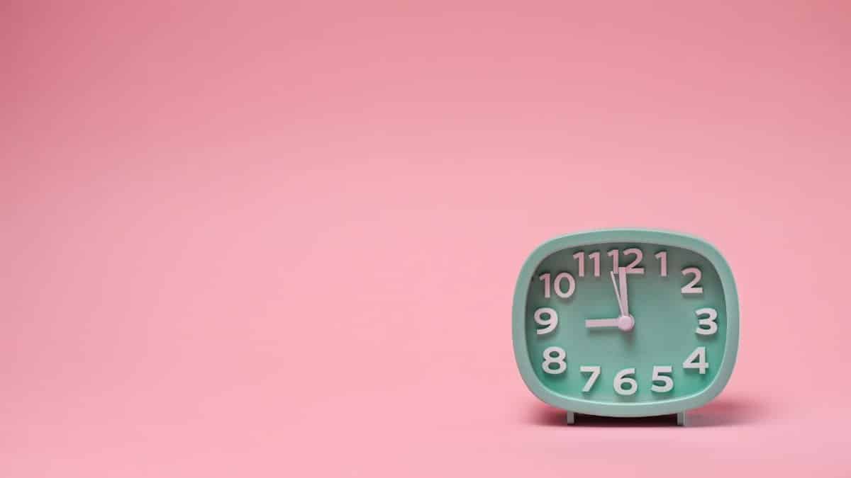 A minimalist mint clock on a pink background offering ample copy space.