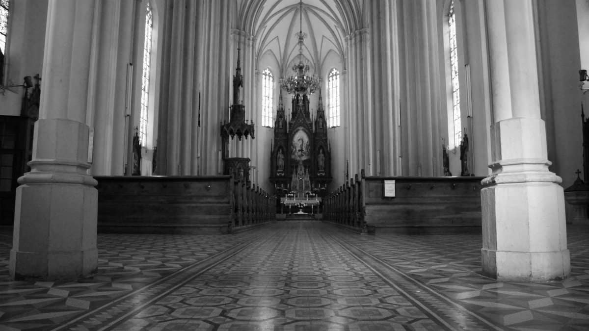 Black and white spacious empty Catholic Church hallway with columns and majestic shrine under arched roof