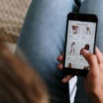 A woman uses her smartphone to shop for clothing online, showcasing digital retail technology.