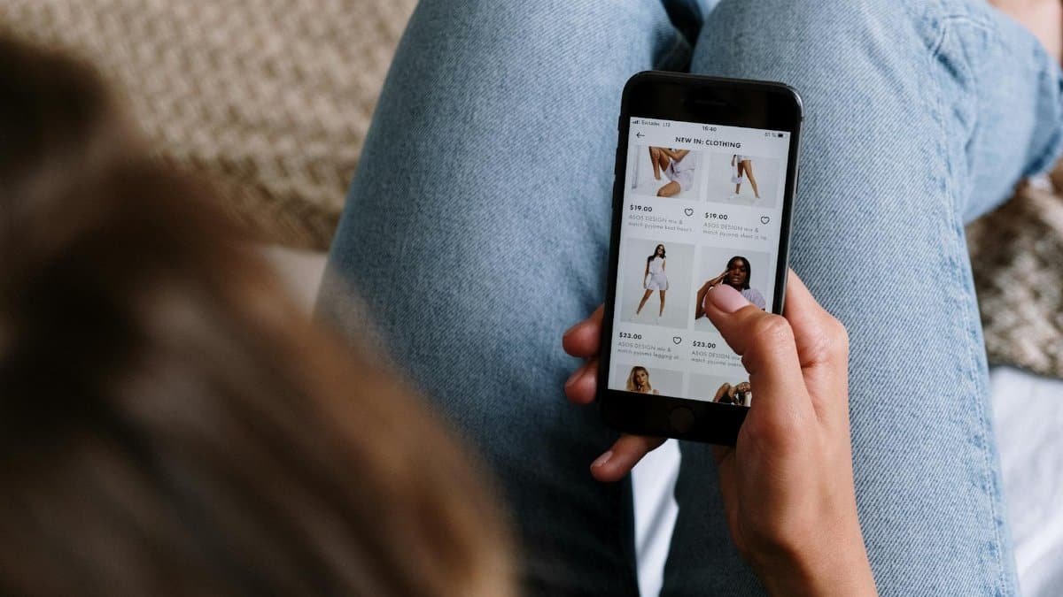 A woman uses her smartphone to shop for clothing online, showcasing digital retail technology.