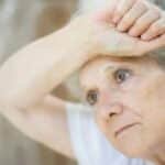 Thoughtful senior woman gazing through a window, symbolizing solitude and reflection.