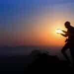 Silhouette of a man holding the sun during a vibrant sunset in Hampi, India.